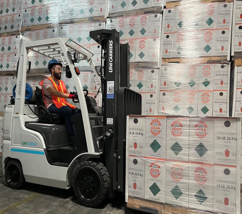 Driver on a forklift about to lift a pallet of refrigerants.